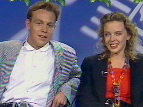 Jason Donovan and Kylie Minogue, pictured from waist up, appearing on a morning talk show in 1989.