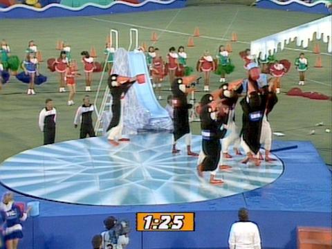 People dressed in penguin costumes holding buckets of water in a tv game show.