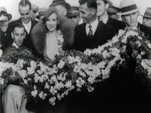Four people hold a garland of flowers intended for Phar Lap after his historic win at Agua Caliente in Mexico, including jockey Billy Elliot and a Hollywood starlet.