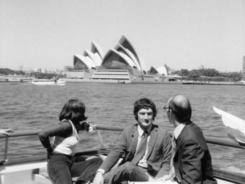 Sydney Opera House is in the background of this shot of three people on a boat.