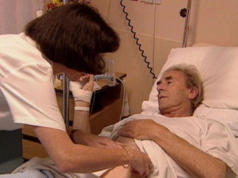 A nurses tends to a hospital patient.