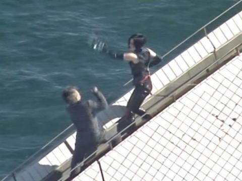 A woman dressed in black is throwing a punch at a man dressed in a black suit.