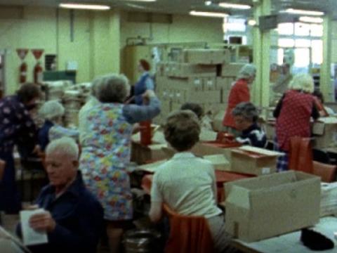 A group of pensioners packing boxes in a warehouse.