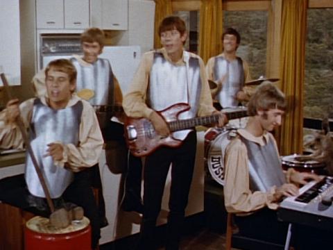 5 musicians playing in a kitchen wearing Ned Kelly style armour.