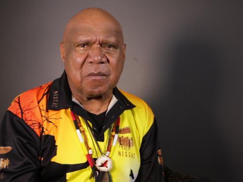 Archie Roach pictured from the chest up, seated and looking directly at camera.