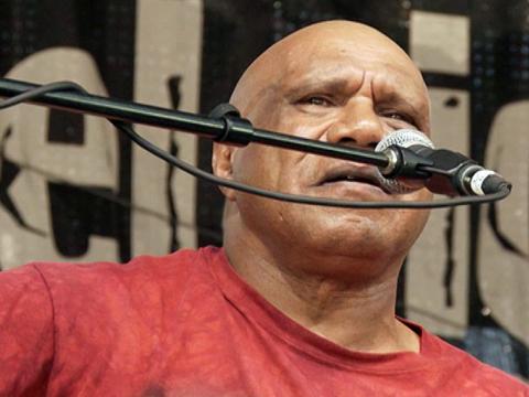 Head and shoulders shot of Indigenous singer-songwriter Archie Roach in front of a microphone
