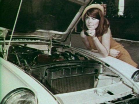 A young woman stands next to a Holden Monaro with the bonnet open