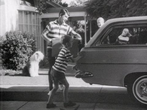 A boy and his father stand behind a Holden car