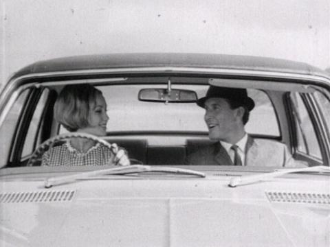 A young woman sits at the wheel of a Holden car