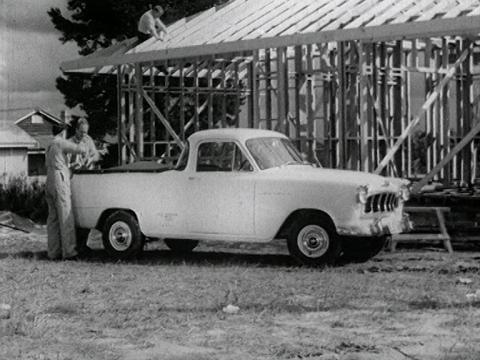 A man stands behind a 1950s model Holden ute