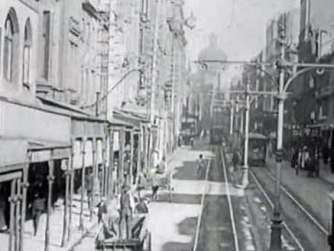 Black and white still of George Street in Sydney with a tram line running down it and horse and carriage