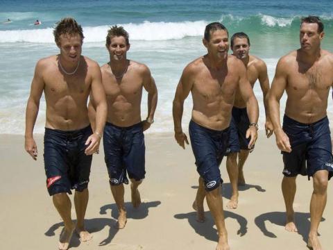 Five lifesavers exit the surf on Bondi Beach in a scene from the TV series Bondi Rescue