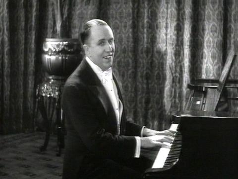 Singer Jack O'Hagan singing at the piano.