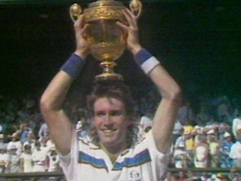 Tennis player Pat Cash holds the Wimbledon trophy above his head.