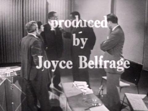 Four men and one woman stand in a semi-circle talking to one another. Text over the image reads: 'produced by Joyce Belfrage'.