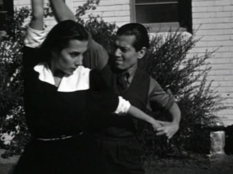 Screenshot of two Ballet Russes dancers performing a routine on the lawn at the front of a beach house, circa 1939.