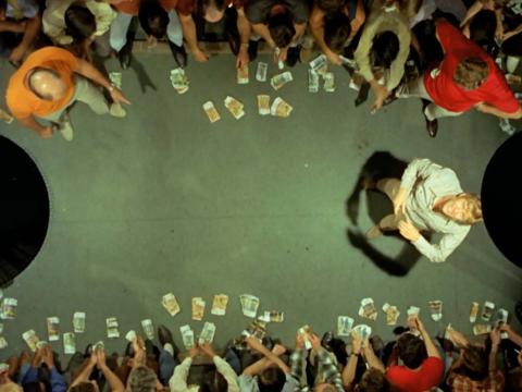 Still image from Wake in Fright showing John Grant, played by Gary Bond, playing two up.