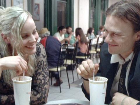 Abbie Cornish and Heath Ledger as Candy and Dan are at McDonalds. They smile at each other in a conspiratorial way.