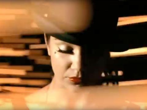 A woman wearing a bowler hat has her eyes closed. Her face is tilted down and she is surrounded by trails of light.