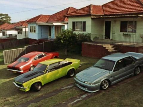 Four cars sit in the driveway of an Australian suburban house.