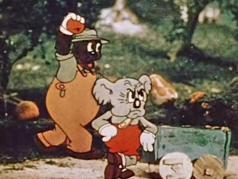Animated still featuring a wombat in a hat and overalls walking through the bush; he's holding a piece of fruit in one hand and approaching a koala with a cranky facial expression, also dressed in overalls and leaning against a wheelbarrow.