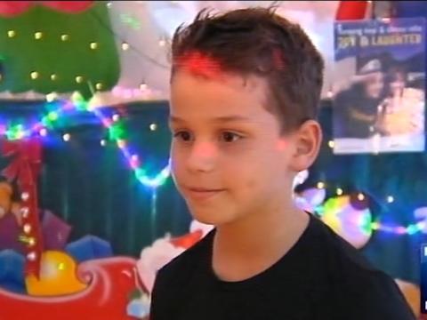 A boy is being interviewed surrounded by Christmas decorations.