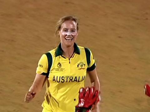 Australian Women's cricketer Ellyse Perry pictured from the waist up in her Australian one-day cricket uniform. She's smiling and running toward the wicket-keeper.