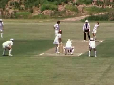 A group of women cricketers and an umpire on a cricket field.