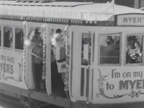 Santa riding on a tram covered in advertising for Myers department store.