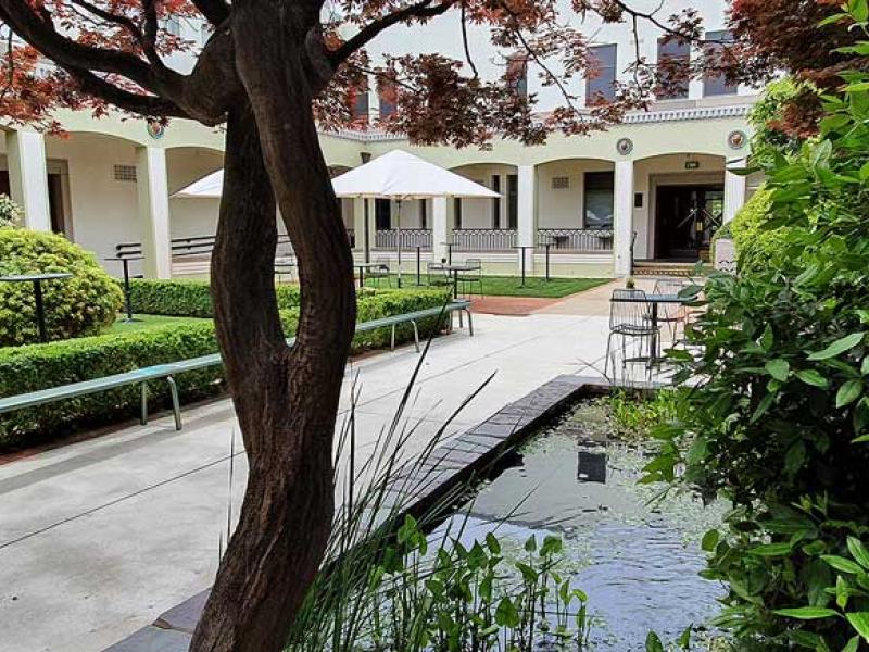 The courtyard at the NFSA with the pond in the front and tables and umbrellas in the background
