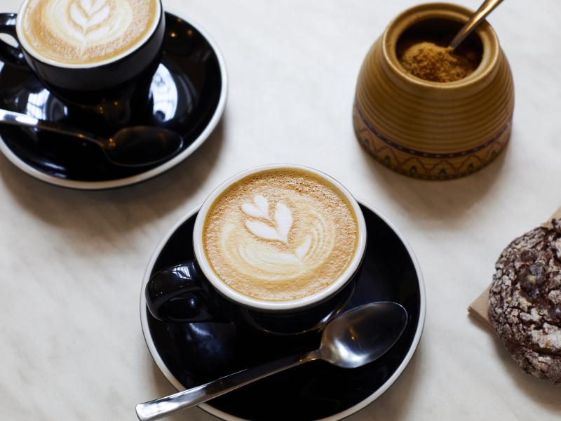 Image of two coffees in mugs on table with teaspoons