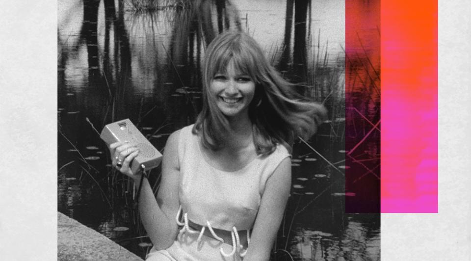 A smiling young woman holding a portable radio.