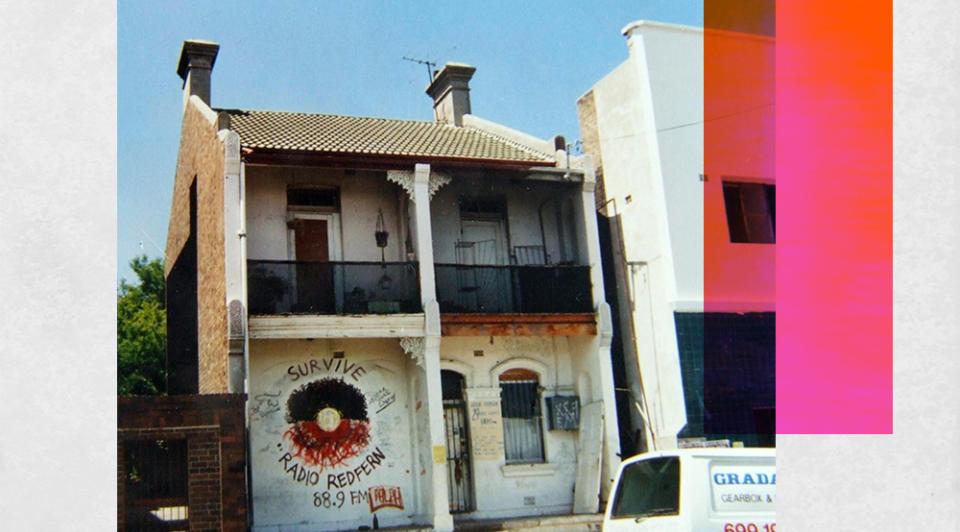 A two-storey house with a spray-painted Aboriginal flag and the slogans Survive, Radio Redfern 88.9FM