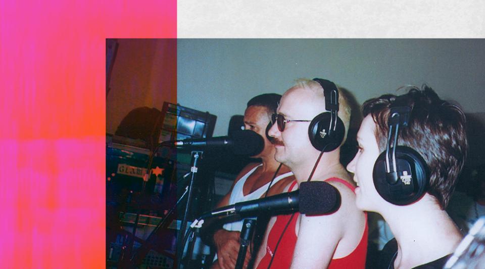Three people wearing headphones and sitting behind microphones in a radio studio.