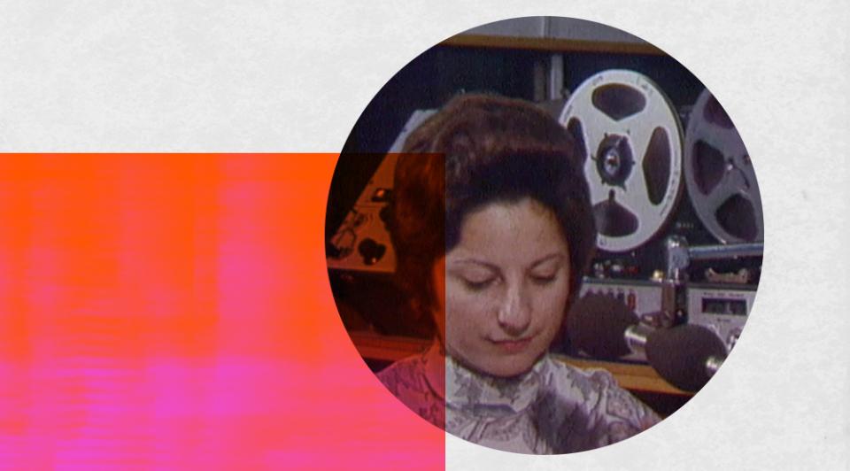 A woman sits at a microphone and in front of a reel-to-reel tape recorder.