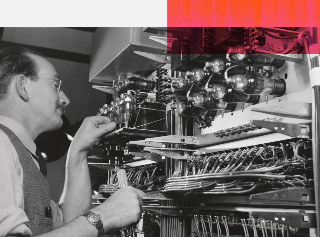 A man standing in front of a console with radio equipment