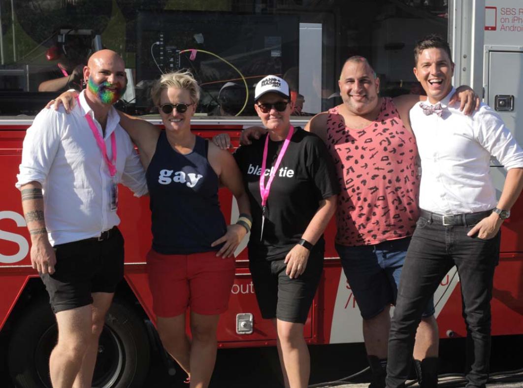 Five people posing in front of a bus during the Sydney Gay and Lesbian Mardi Gras.
