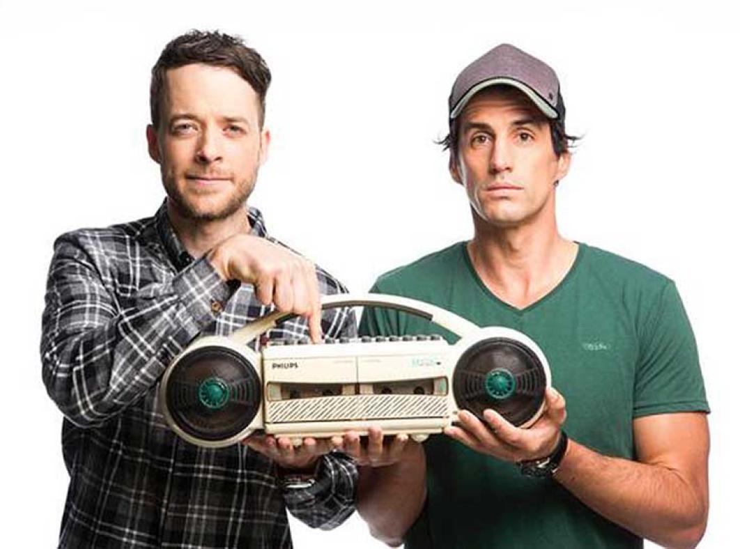 Promotional image of radio personalities Hamish Blake and Andy Lee holding a portable cassette player/recorder.