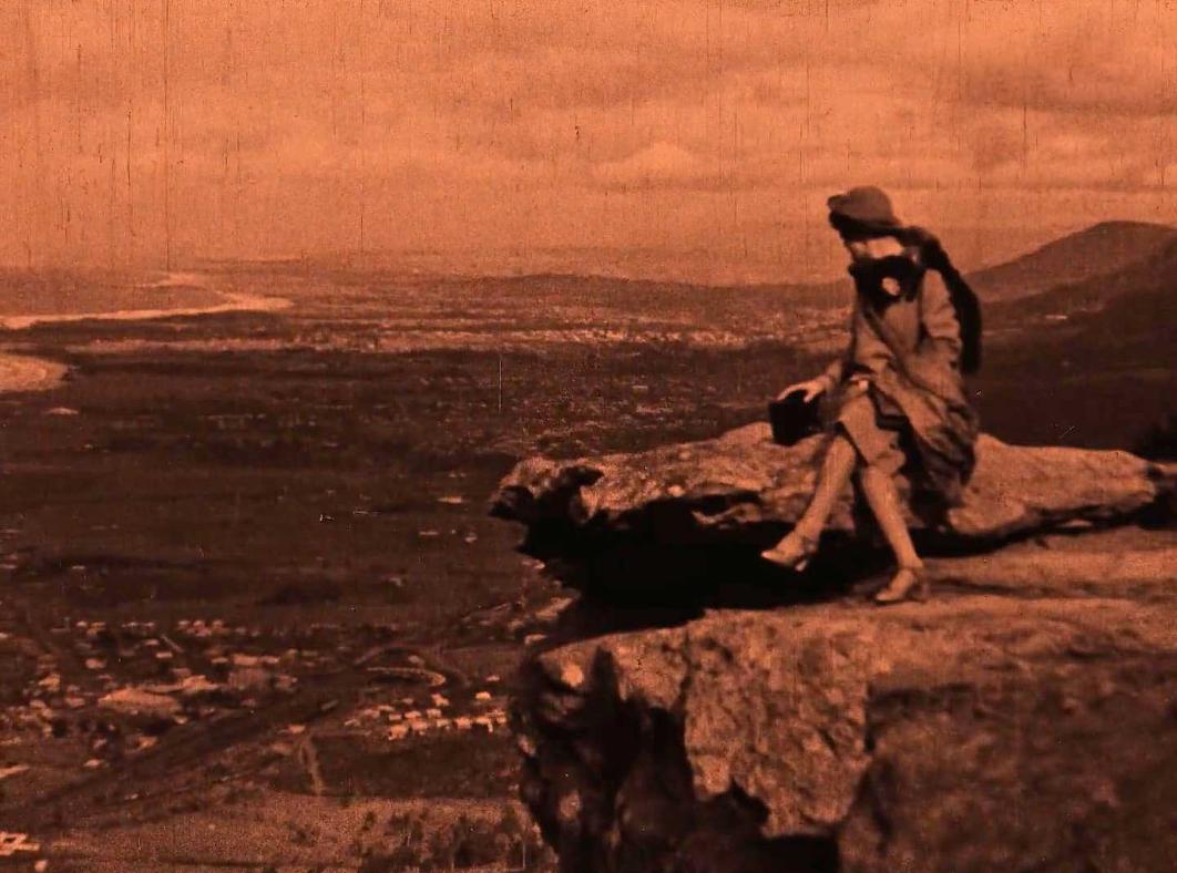 A woman sitting on some rocks looking out over the ocean.