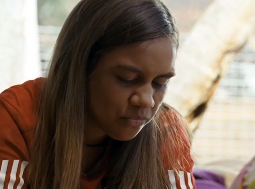 Close up of a teenage First Nations girl looking downwards.