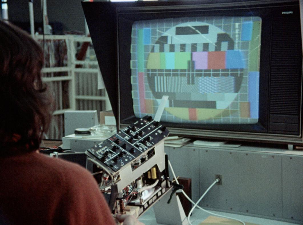 A person looking at a large monitor with a colour tv test pattern on it.