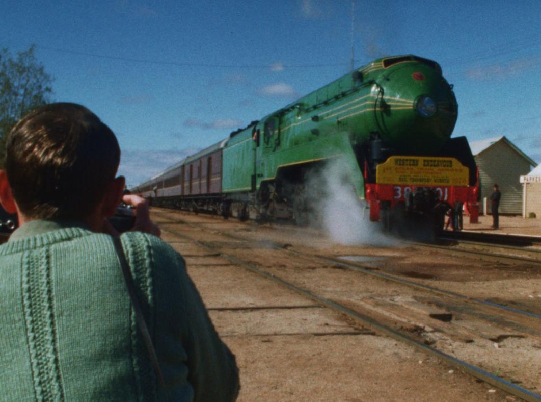 A child holding a camera takes a photo of an approaching 3801 steam train