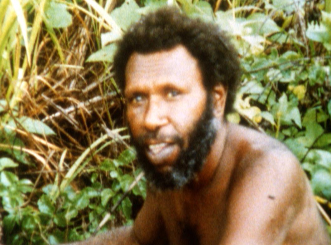 Eddie Mabo looking at the camera and smiling while he does gardening work.
