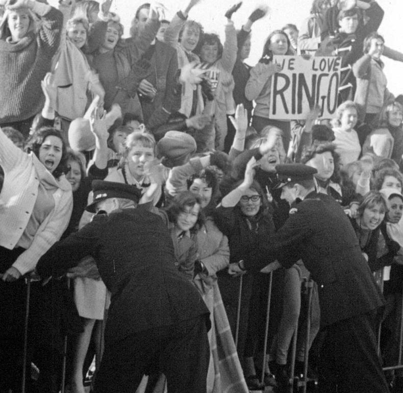 A large crowd of screaming teenagers behind a barrier awaiting the arrival of The Beatles in Melbourne