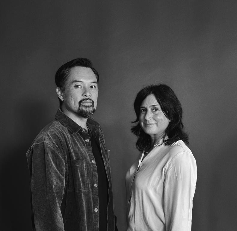 Artists Melvin J. Montalban and Leila Jeffreys stand facing each other with their heads turned towards the camera 