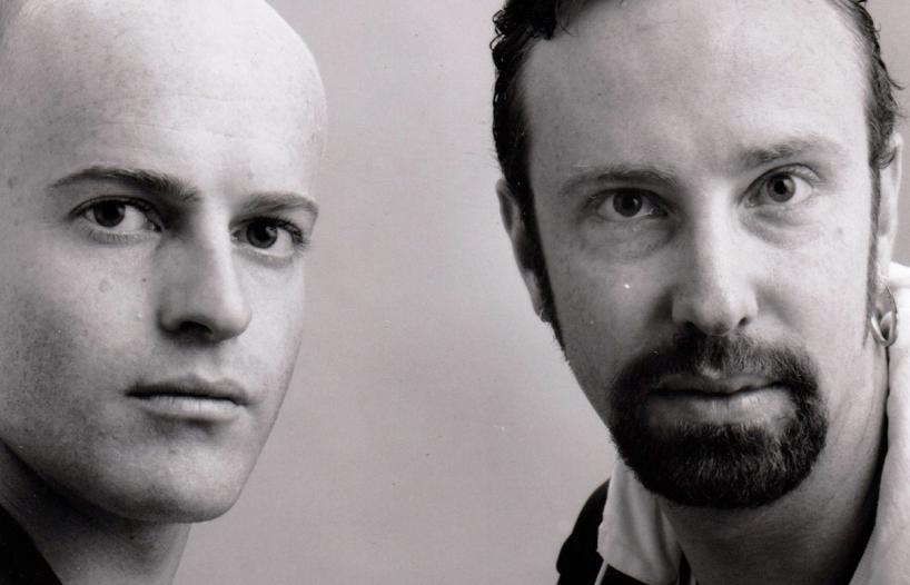 Close up of two men standing side by side and looking intently into the camera.