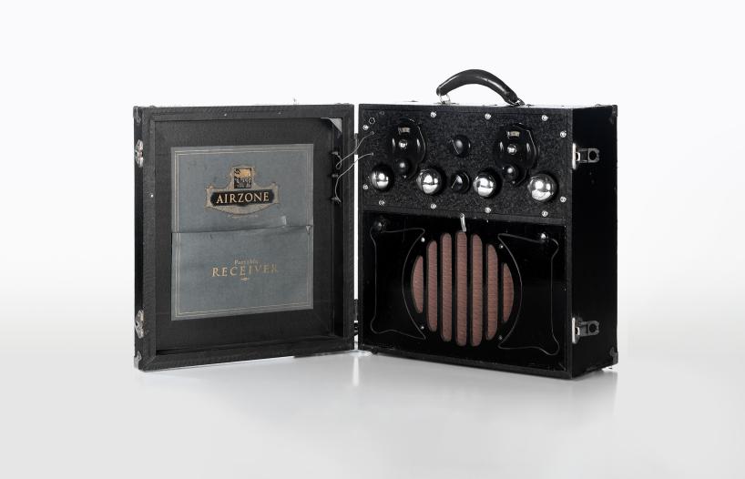 A radio receiver from the 1920s, housed in a wooden box carry case with a handle on top.