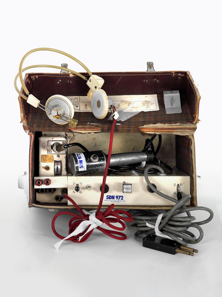 A portable radio unit featuring headphones and a microphone inside a carry case. There is a 5DN radio logo on it.