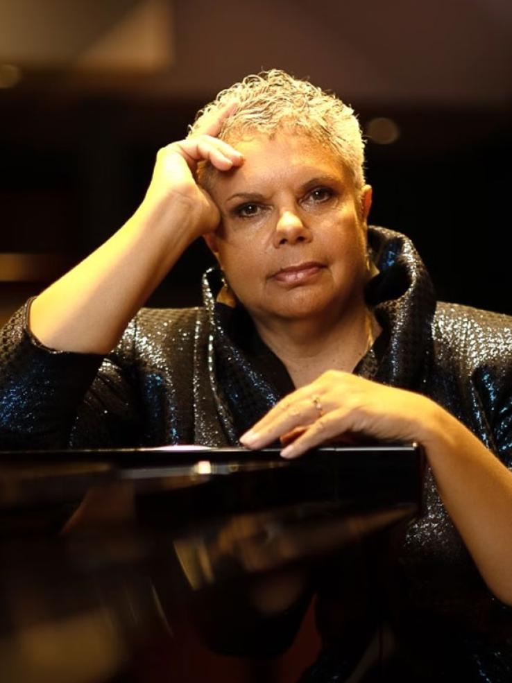 Opera singer Deborah Cheetham leaning on a piano