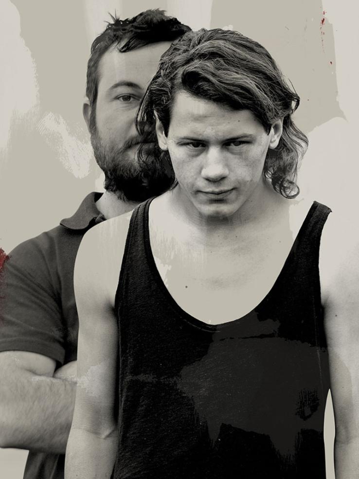 Part of a poster for the film 'Snowtown' showing a teenage boy facing the camera, he's partially obscuring a bearded man standing behind him with his arms folded.